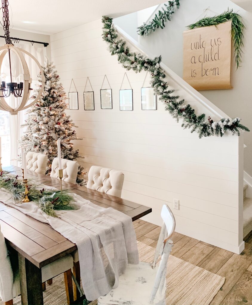 dining room with flocked christmas tree and garland along the stairs