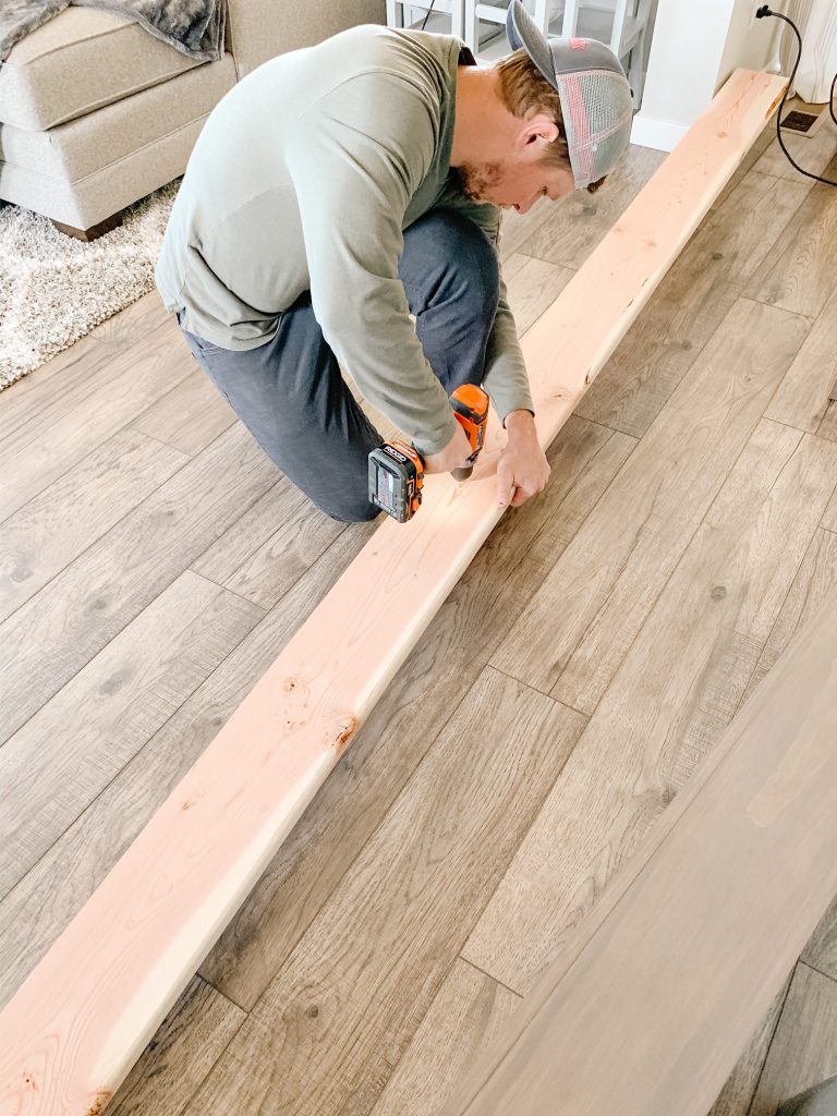 man drilling holes into wood board