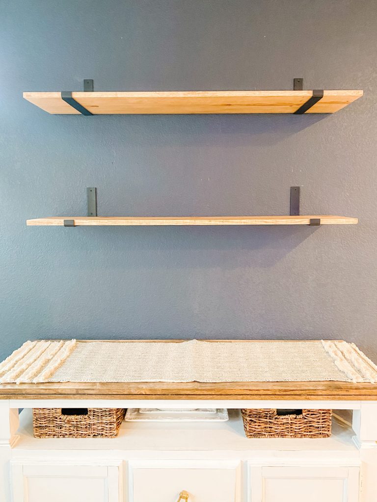 stained wood shelves with black brackets on navy wall