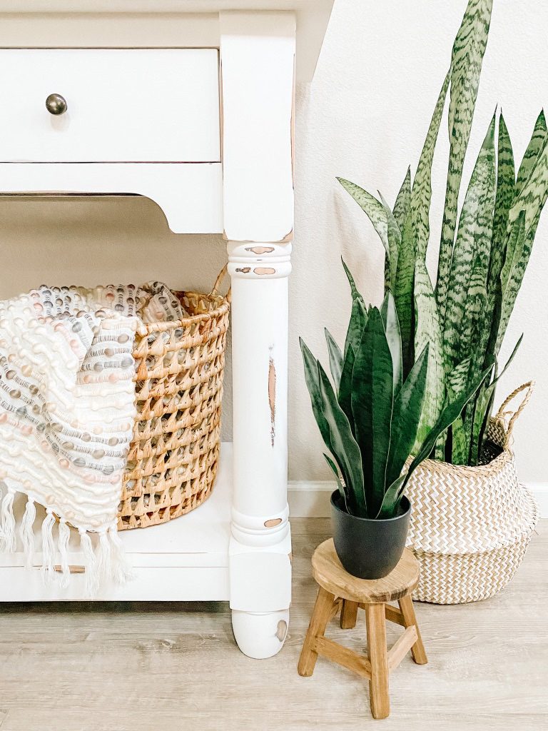 white console table with basket and throw snake plant in basket