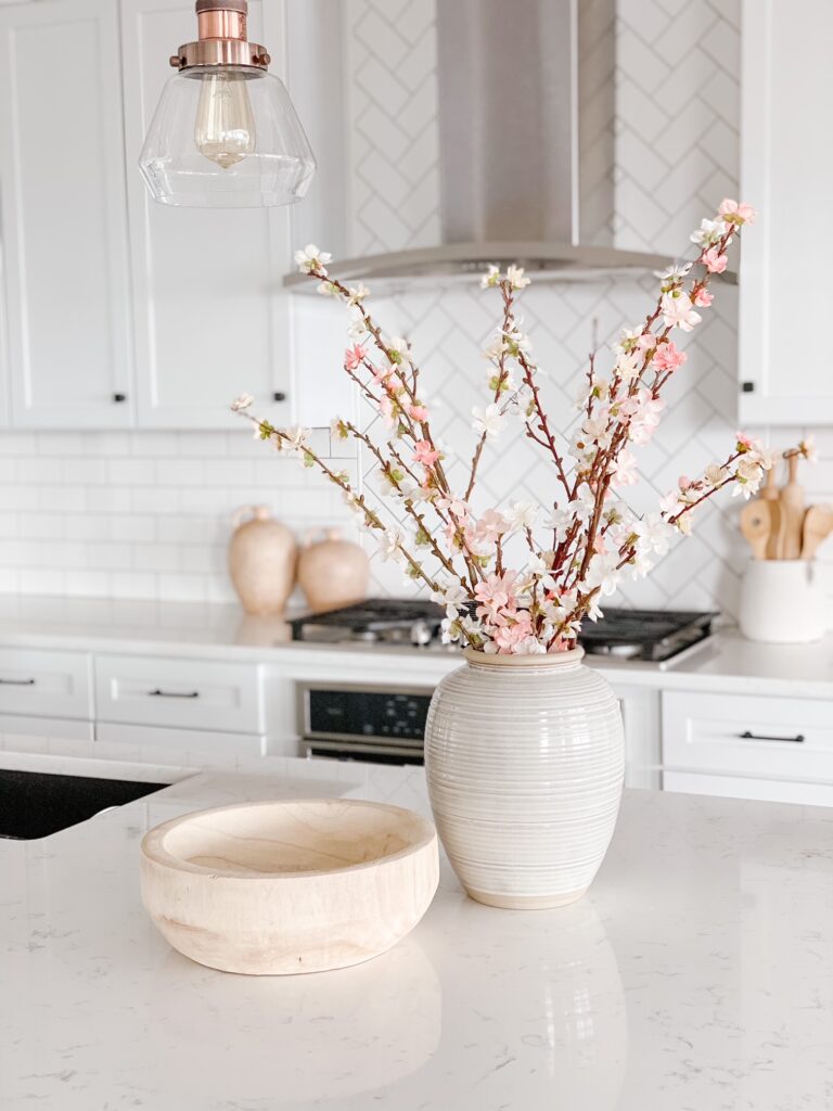 Spring faux blossom stems in a vase in the kitchen is a great way to add color to your neutral home!