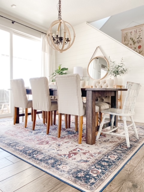 Dining room with farmhouse table, tufted dining chairs and ruggable rug.