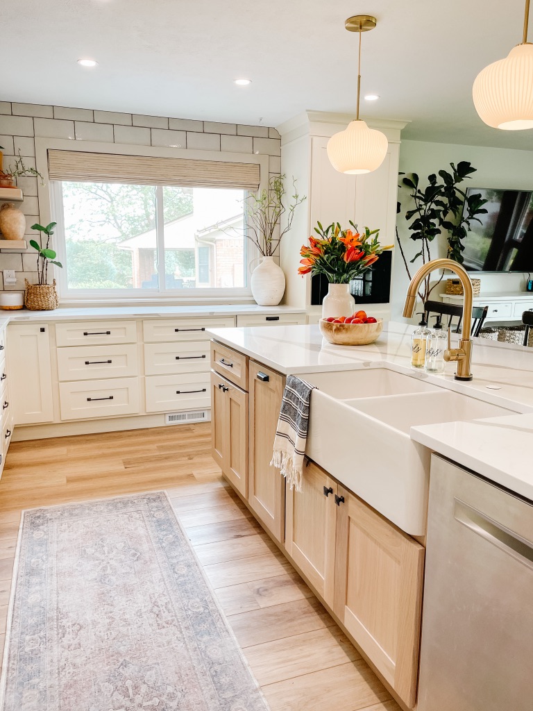 kitchen remodel with large white farmhouse sink and gold faucet and white oak cabinets at island