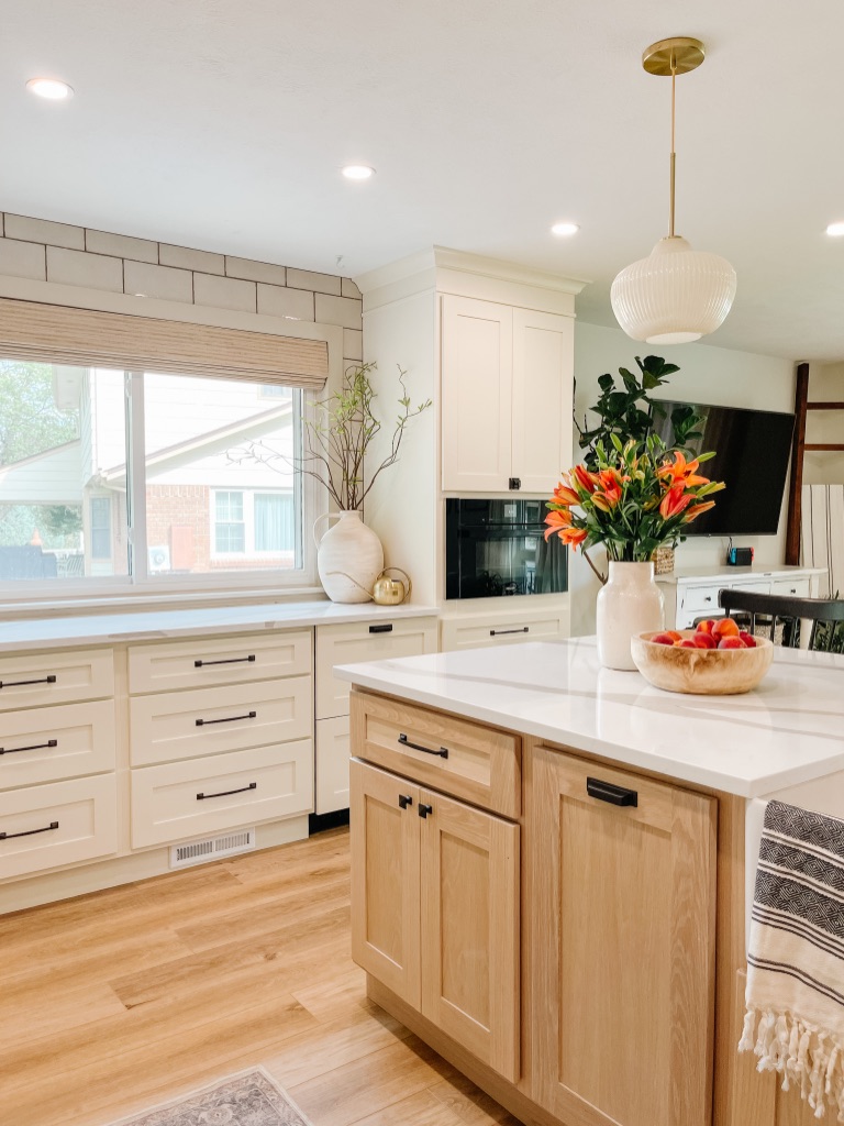 decorate your kitchen countertops with statement pieces like large vases with greenery and faux stems, and a big wooden bowl for fruit