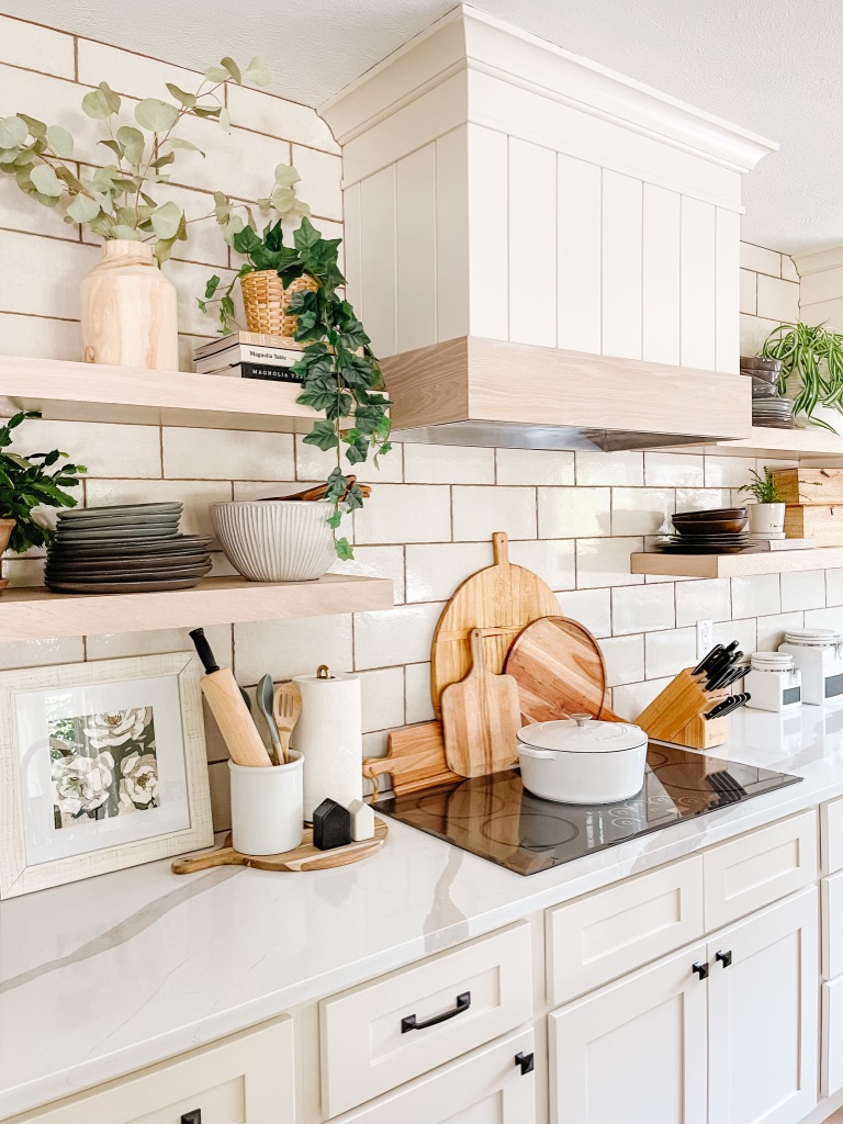 style your kitchen stove area by layering large wooden cutting boards behind your cooktop and add a white dutch oven