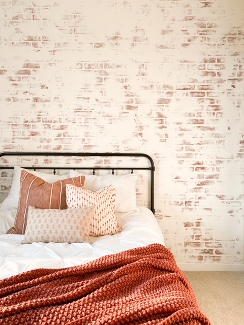 White washed brick wall in bedroom.