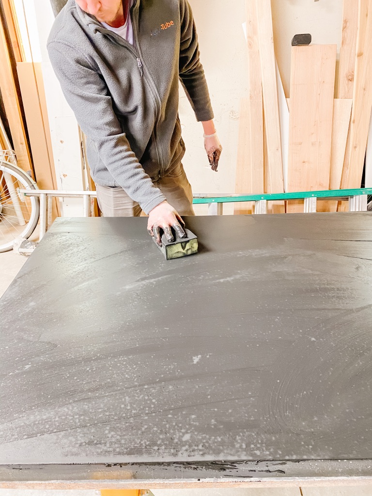 Filling holes in black DIY Concrete Dining Table with Z Counter-Patch slurry mixture