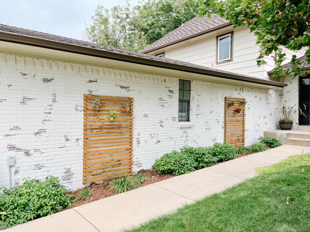 easy DIY slatted wood trellises against a white brick wall with hanging terra cotta pots with vines