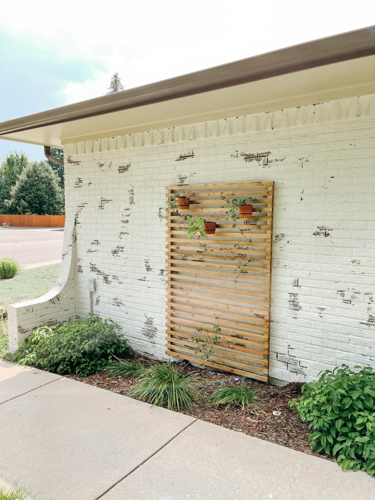 simple and affordable wood slat trellis against german schmear white brick