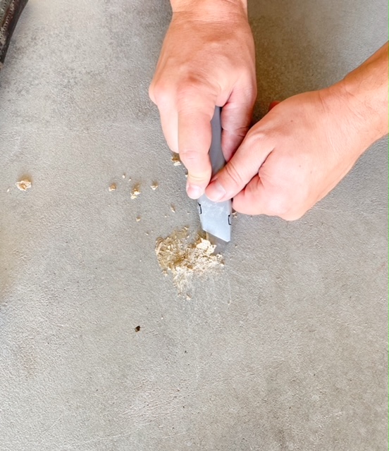 scraping off glue from garage floor to get ready for epoxy