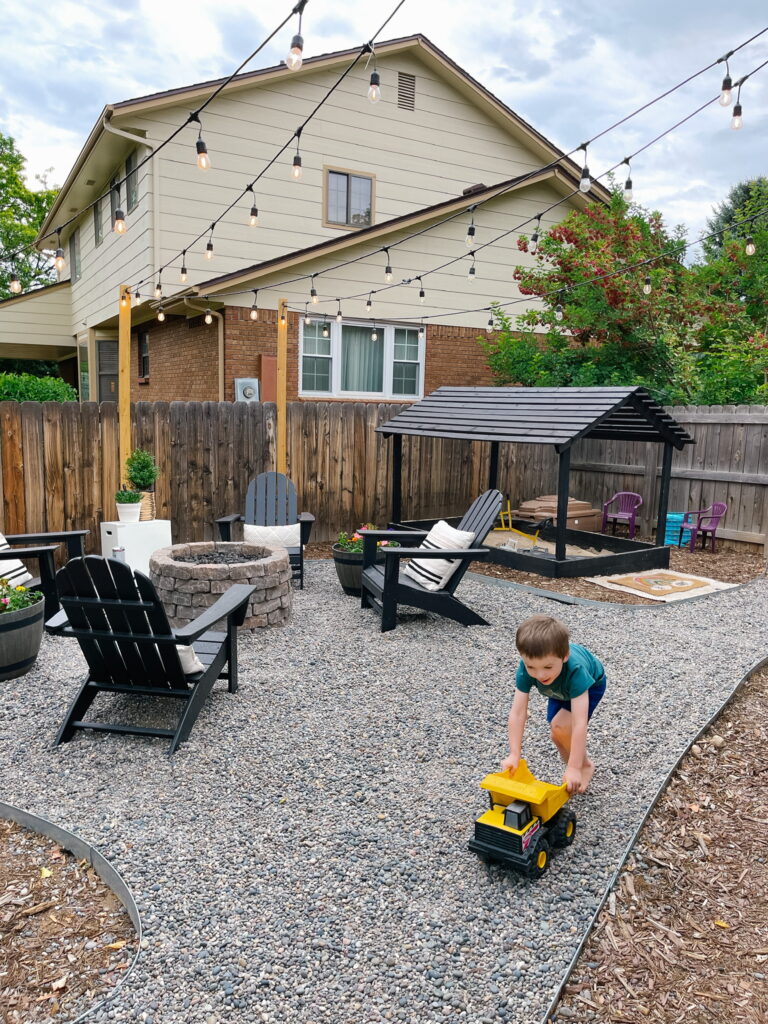 Small backyard makeover with DIY Propane Fire Pit Area with Polywood Black Adirondack Chairs from Wayfair and DIY Sandbox with Slatted Roof