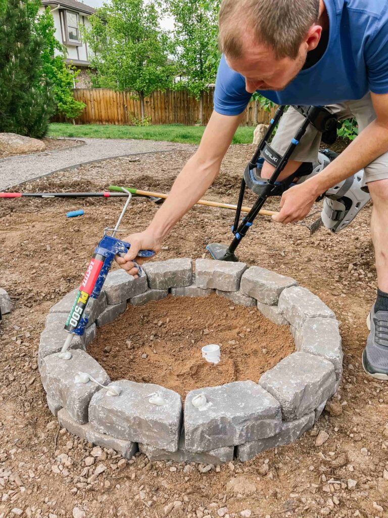 Apply landscaping adhesive between layers of stone at Fire Pit 