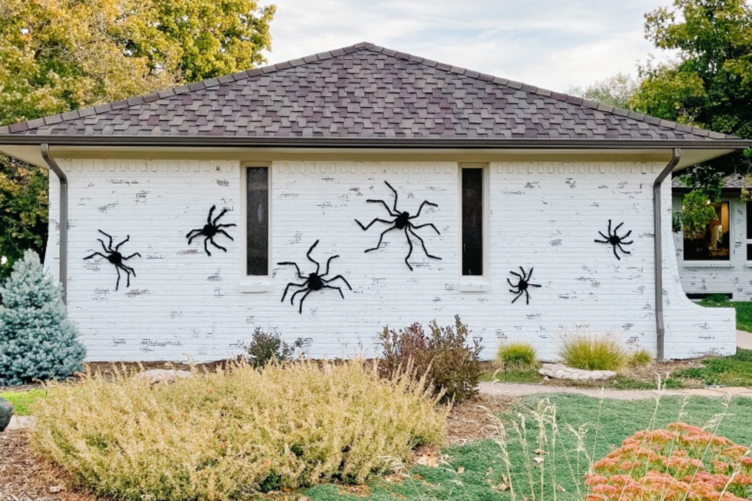 simple halloween decorations with large fuzzy spiders on house exterior with white brick